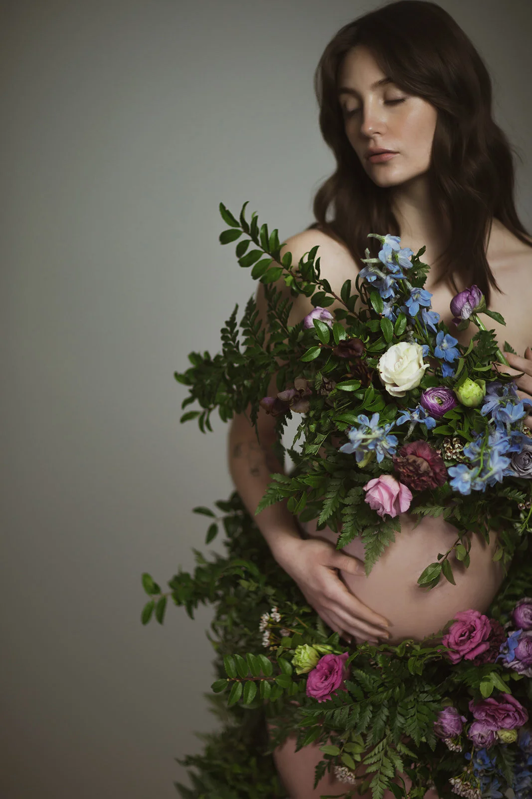 Greek inspired maternity shoot with a wearable floral garland filled with blue delphinium, lavender spray roses, plum ranunculus, blush and fuchsia roses. Designed by wedding florist Rosemary & Finch in Nashville.