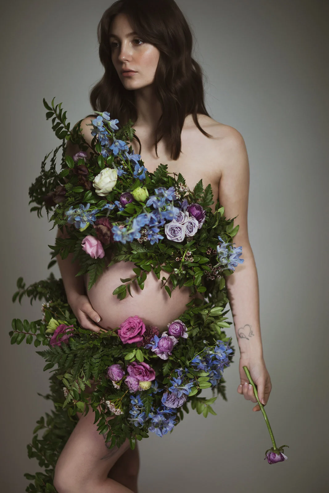 Greek inspired maternity shoot with a wearable floral garland filled with blue delphinium, lavender spray roses, plum ranunculus, blush and fuchsia roses. Designed by wedding florist Rosemary & Finch in Nashville.