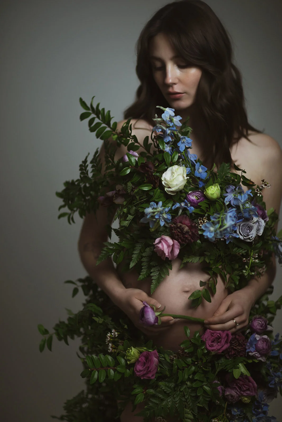 Greek inspired maternity shoot with a wearable floral garland filled with blue delphinium, lavender spray roses, plum ranunculus, blush and fuchsia roses. Designed by wedding florist Rosemary & Finch in Nashville.