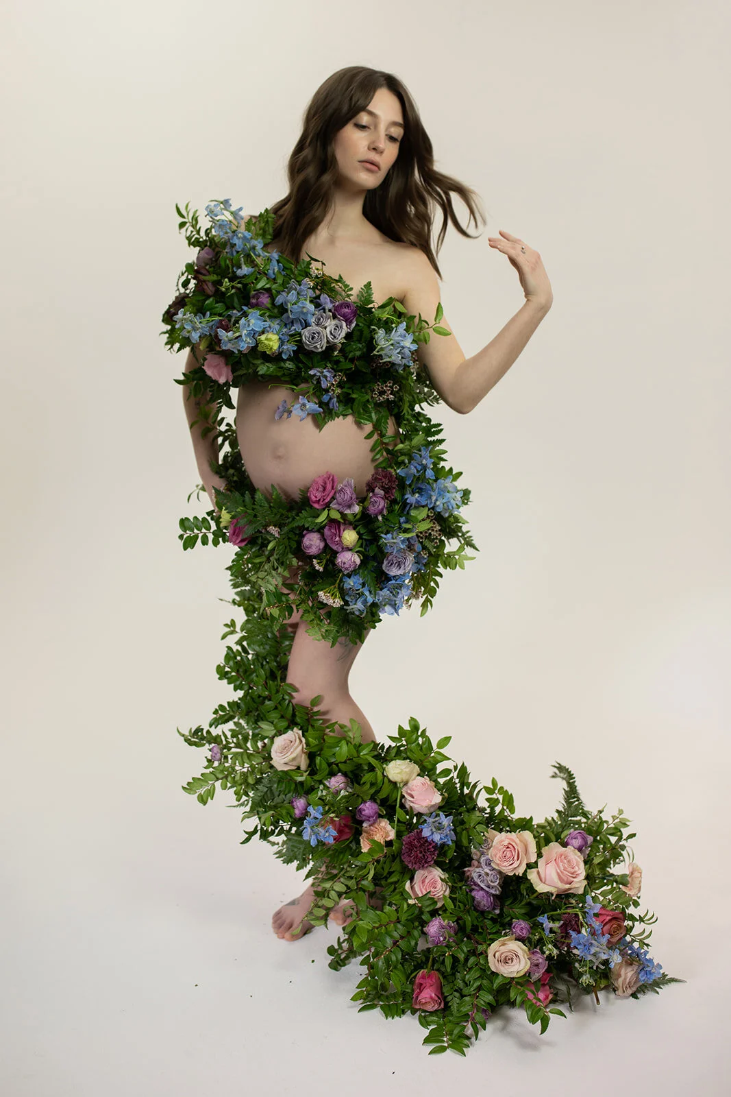 Greek inspired maternity shoot with a wearable floral garland filled with blue delphinium, lavender spray roses, plum ranunculus, blush and fuchsia roses. Designed by wedding florist Rosemary & Finch in Nashville.