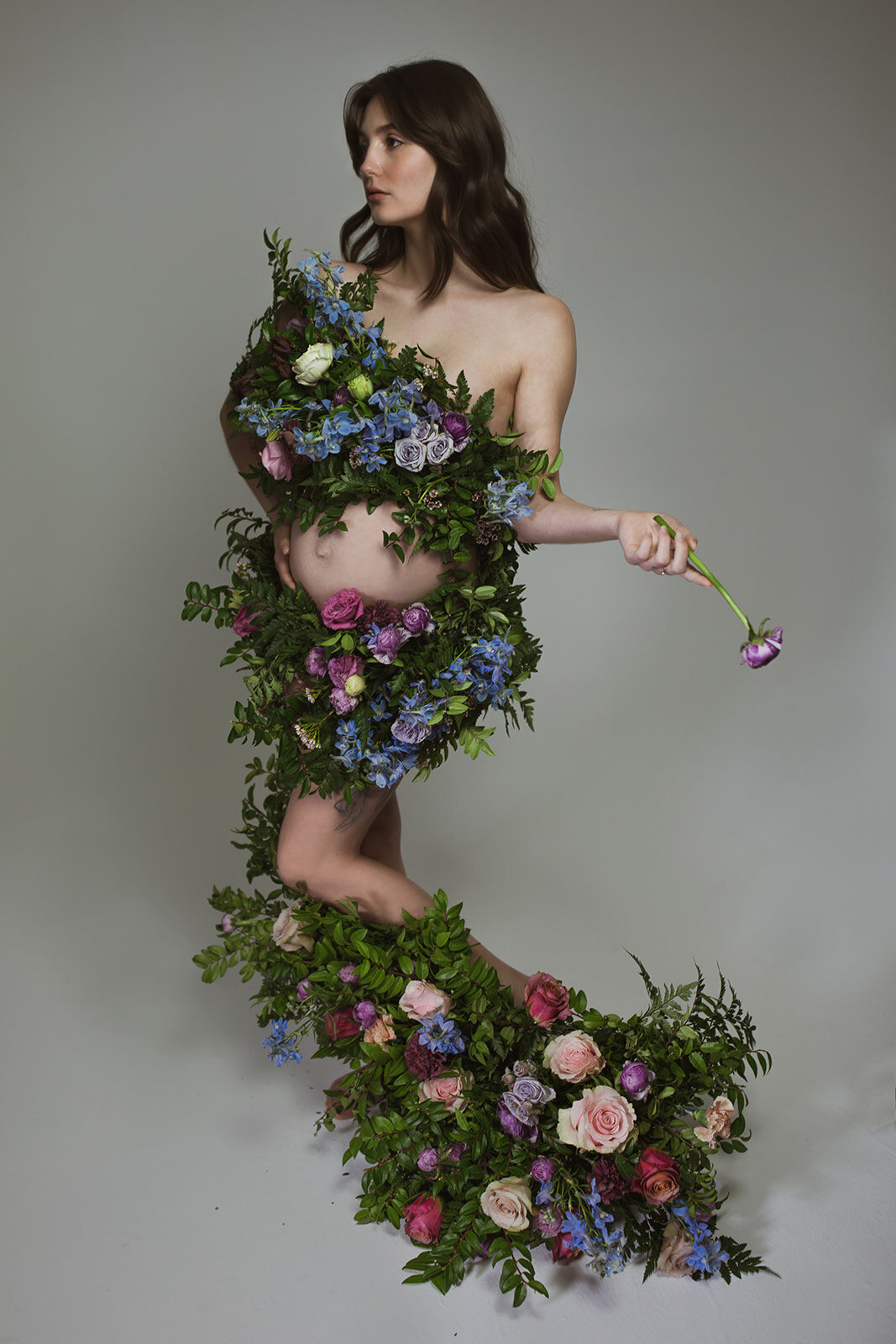 Greek inspired maternity shoot with a wearable floral garland filled with blue delphinium, lavender spray roses, plum ranunculus, blush and fuchsia roses. Designed by wedding florist Rosemary & Finch in Nashville.