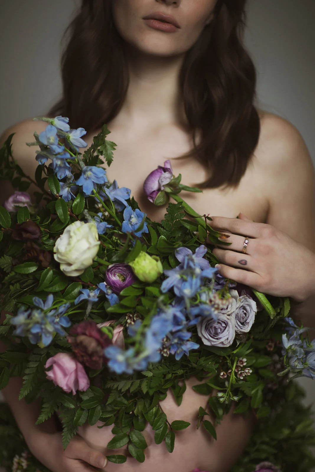 Greek inspired maternity shoot with a wearable floral garland filled with blue delphinium, lavender spray roses, plum ranunculus, blush and fuchsia roses. Designed by wedding florist Rosemary & Finch in Nashville.