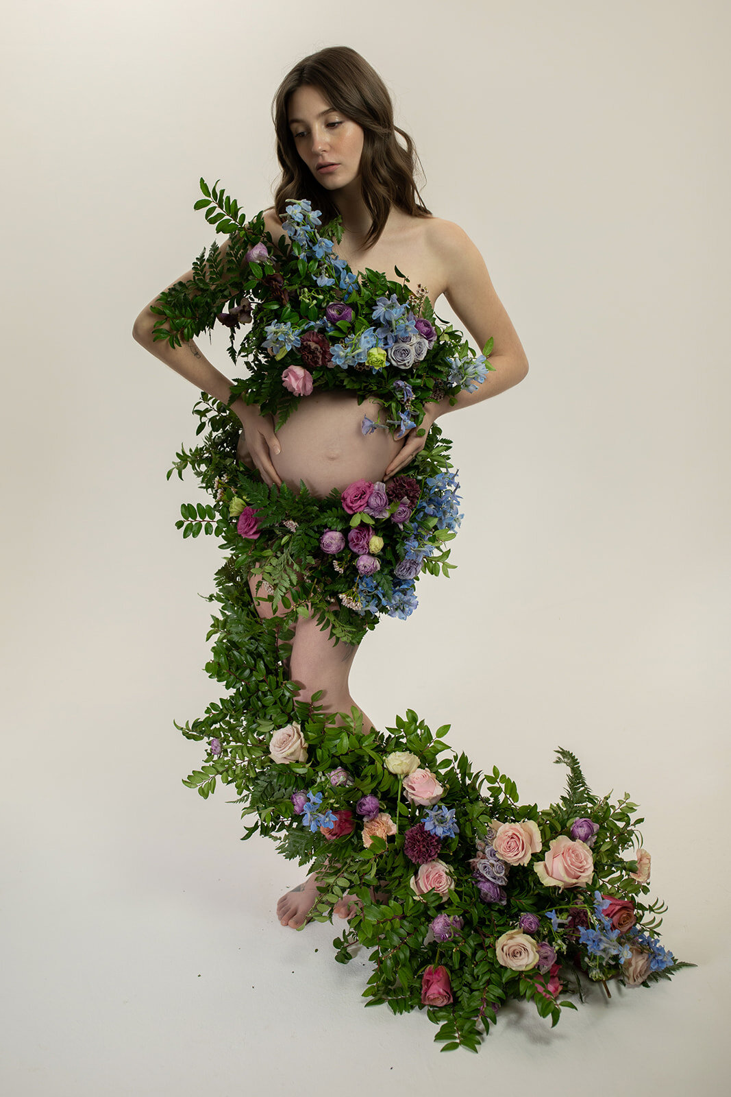 Greek inspired maternity shoot with a wearable floral garland filled with blue delphinium, lavender spray roses, plum ranunculus, blush and fuchsia roses. Designed by wedding florist Rosemary & Finch in Nashville.