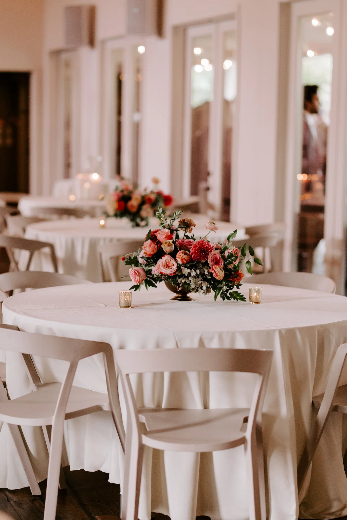 Bright and summery centerpieces filled with coral zinnias, fuchsia and blush dahlias, tangerine ranunculus, petal-heavy roses, pink snowberry, fluffy hydrangea, and sprawling smilax vine. Designed by Nashville wedding floral designer, Rosemary & Fin…
