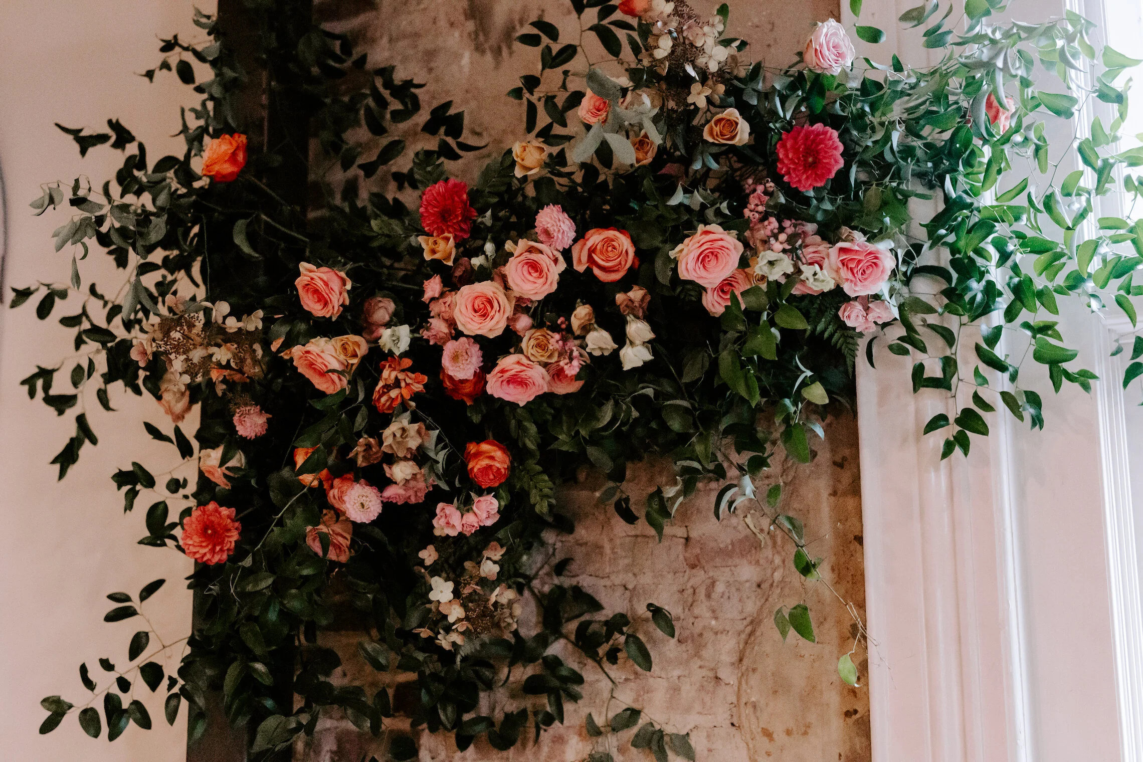 This wedding featured a stunning ceremony arch and a moss and floral wall installation. Blooms used were coral zinnias, fuchsia and blush dahlias, tangerine ranunculus, petal-heavy roses, pink snowberry, and sprawling smilax vine. Designed by Nashvi…