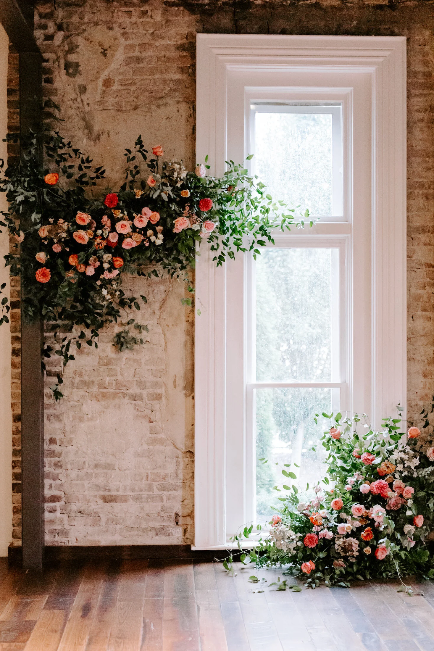 This wedding featured a stunning ceremony arch and a moss and floral wall installation. Blooms used were coral zinnias, fuchsia and blush dahlias, tangerine ranunculus, petal-heavy roses, pink snowberry, and sprawling smilax vine. Designed by Nashvi…