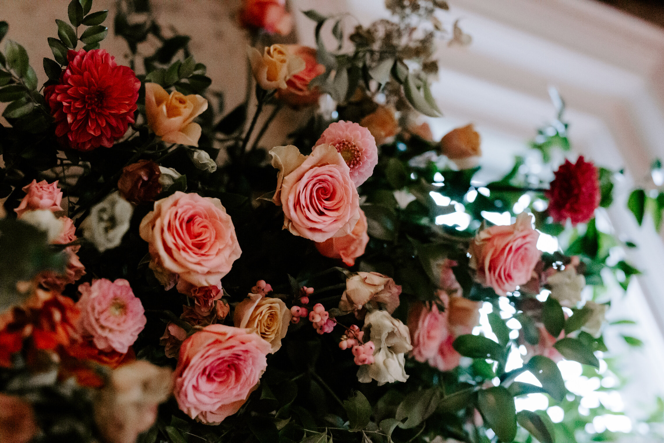 This wedding featured a stunning ceremony arch and a moss and floral wall installation. Blooms used were coral zinnias, fuchsia and blush dahlias, tangerine ranunculus, petal-heavy roses, pink snowberry, and sprawling smilax vine. Designed by Nashvi…