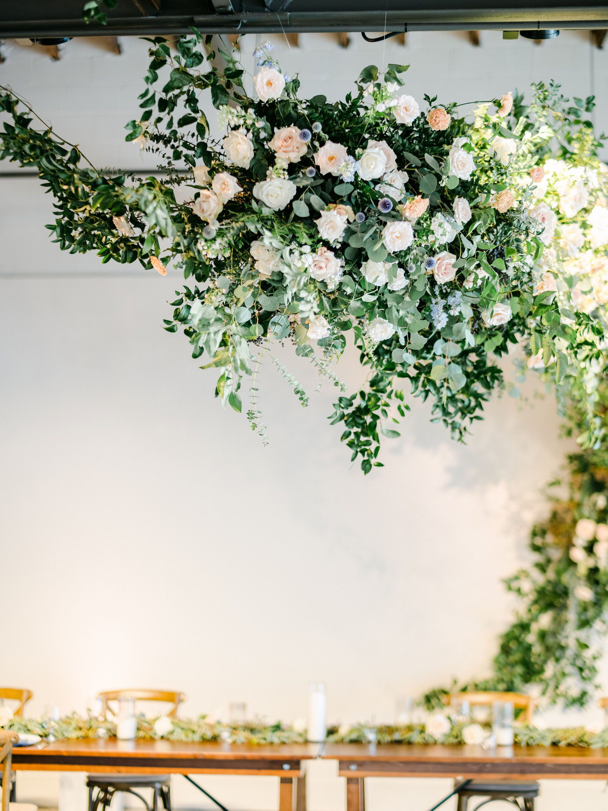 A dramatic and winding installation full of movement that grew up the back wall, across the head table and out into the dance floor. Filled with white and blush garden roses, spray roses, delphinium, blue thistle, heirloom carnations, eucalyptus and…