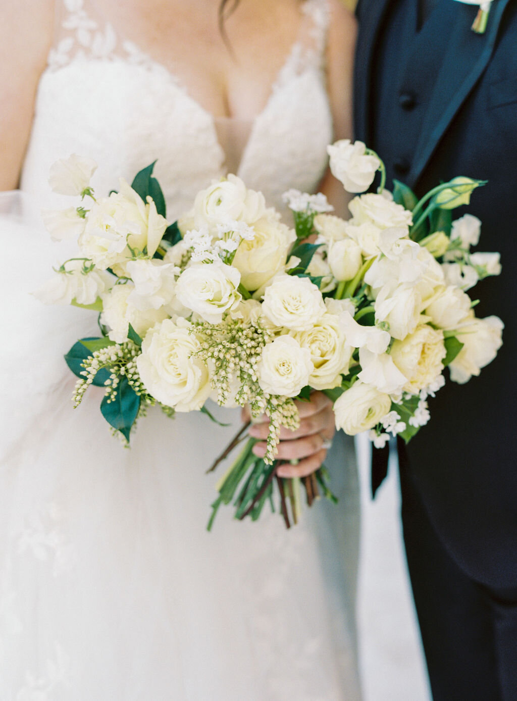 This wintery bridal bouquet is filled with white ice roses, fluffy ranunculus, draping pieris, majolica spray roses, white sweet pea, ivory lisianthus, and patience garden rose. Designed by florist Rosemary & Finch in Nashville, TN.