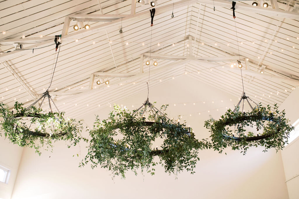Chandeliers covered in wild smilax for a natural overhead installation. Designed by florist Rosemary & Finch in Nashville, TN.
