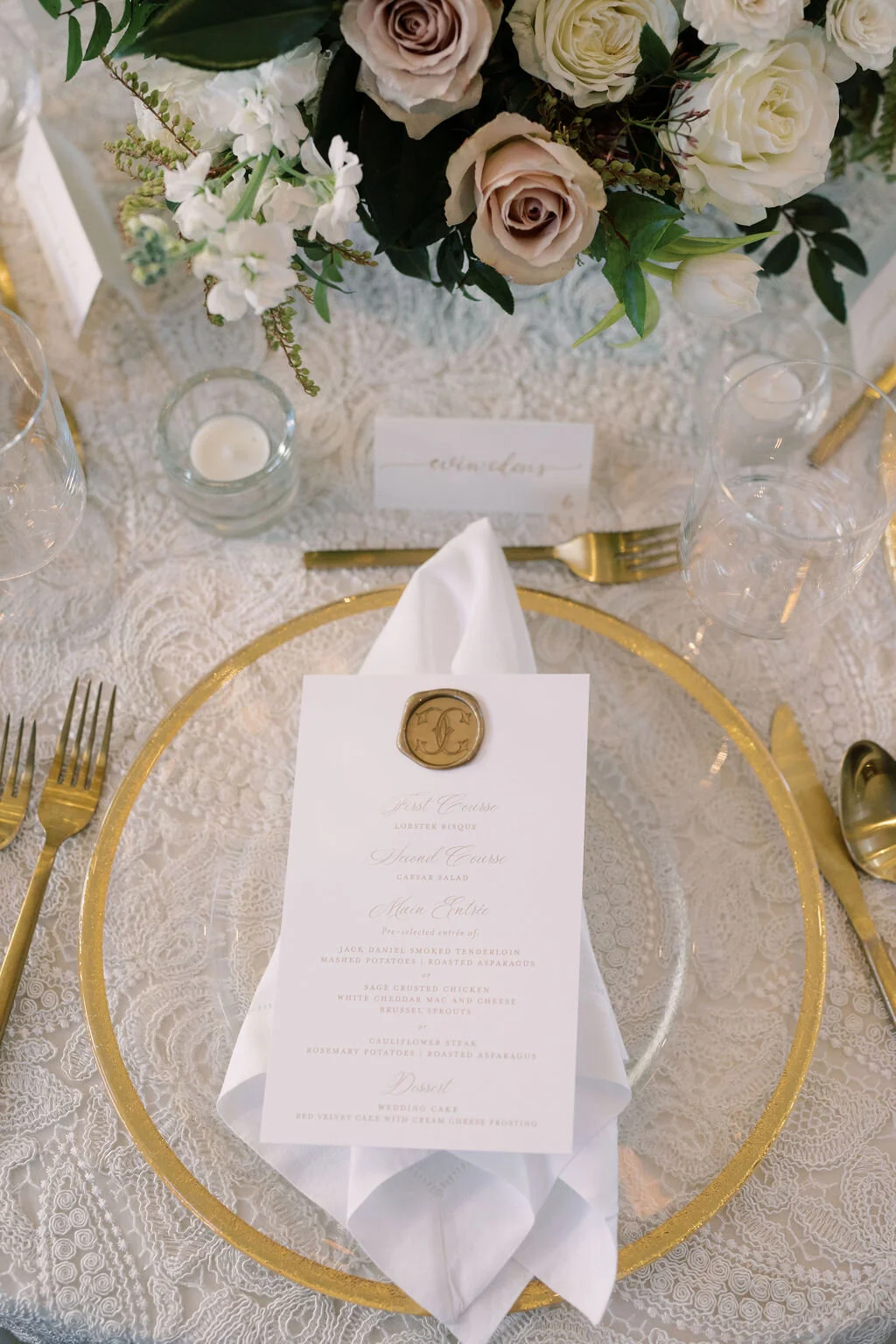 This twinkling reception is filled with taupe tapers in collected brass candlesticks. Centerpieces filled with delicate blooms of quicksand roses, white ice roses, majolica spray roses, fluffy ranunculus, white stock, delicate sweet pea and natural …