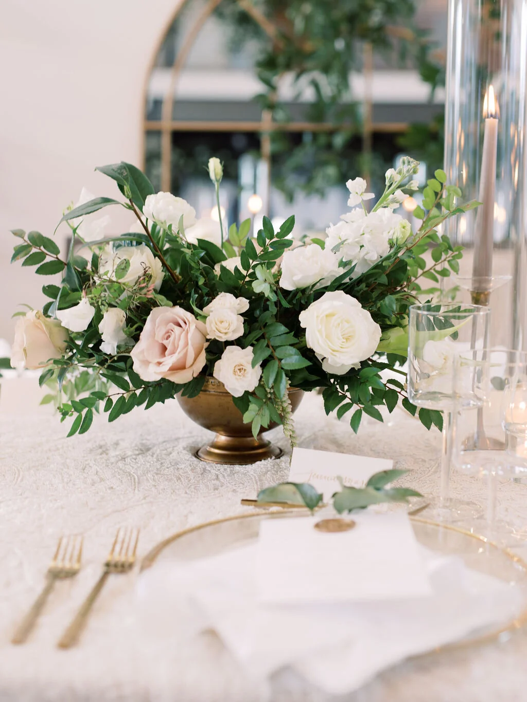 This twinkling reception is filled with taupe tapers in collected brass candlesticks. Centerpieces filled with delicate blooms of quicksand roses, white ice roses, majolica spray roses, fluffy ranunculus, white stock, delicate sweet pea and natural …