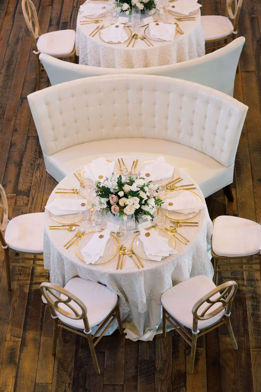 This twinkling reception is filled with taupe tapers in collected brass candlesticks. Centerpieces filled with delicate blooms of quicksand roses, white ice roses, majolica spray roses, fluffy ranunculus, white stock, delicate sweet pea and natural …