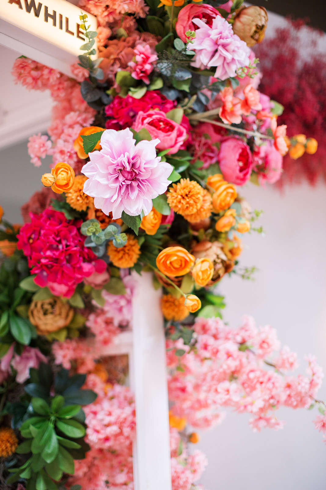 This whimsical, summery floral installation perfectly sets off this crisp white phone booth. Flowers used here are pink cherry blossom, blush dahlia, orange ranunculus, mauve hydrangea, and lush colorful blooms. Designed for 5th and Broadway in Nash…