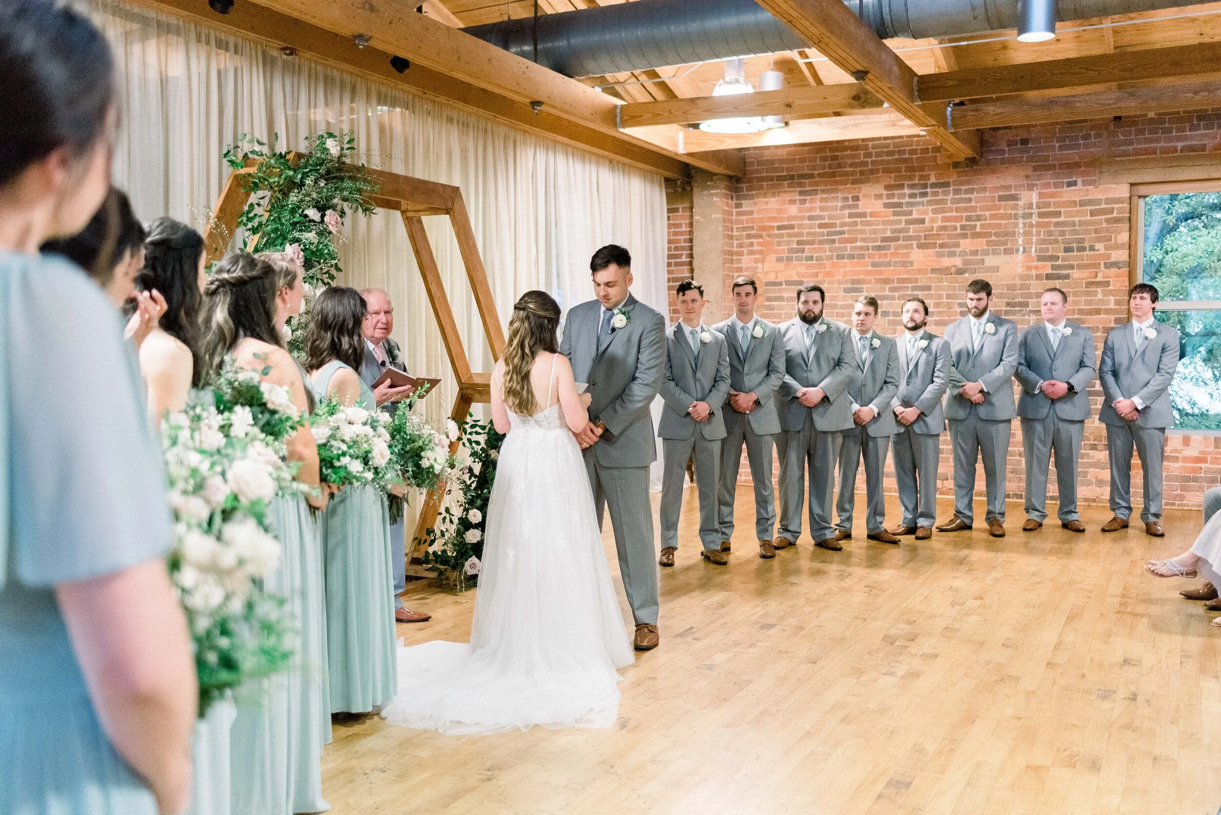 A hexagon arch makes the perfect ceremony backdrop. Blooms used here are blush quicksand roses, cream garden roses, white ranunculus, spray roses, and lush greenery. Designed by florist Rosemary & Finch in Nashville, TN.