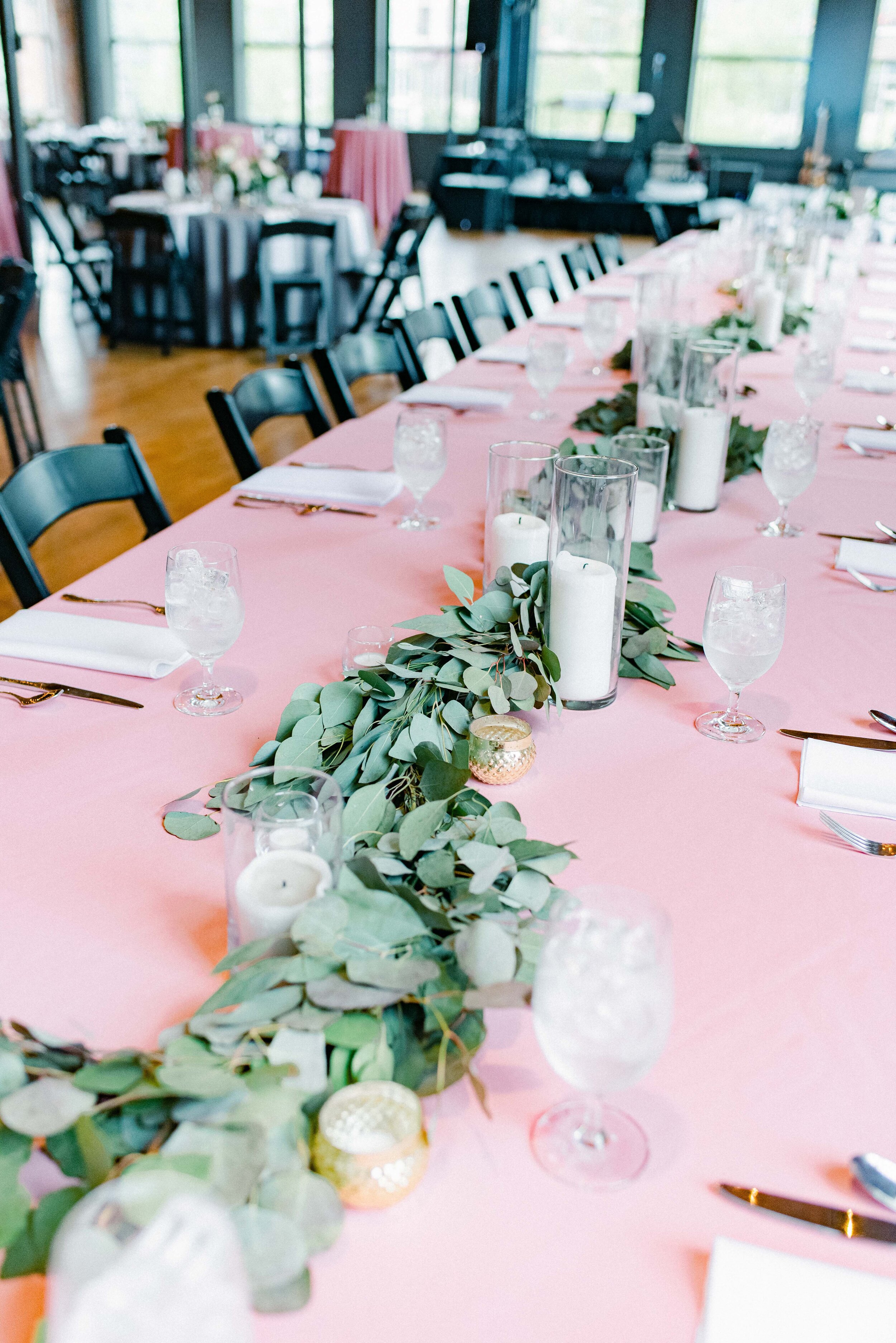 Table decor for this stunning wedding consisted of several different components. Round tables held lanterns adorned with blush and cream roses and lush greenery. Long, farm tables had garlands of eucalyptus and twinkling candles. Centerpieces filled…