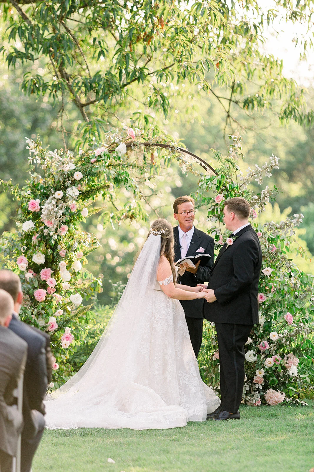 A fairytail arch filled with blush and ivory garden roses, majolica spray roses, champagne roses, eleagnus, and lush sprawling greenery. Designed by Rosemary & Finch in Nashville, TN.