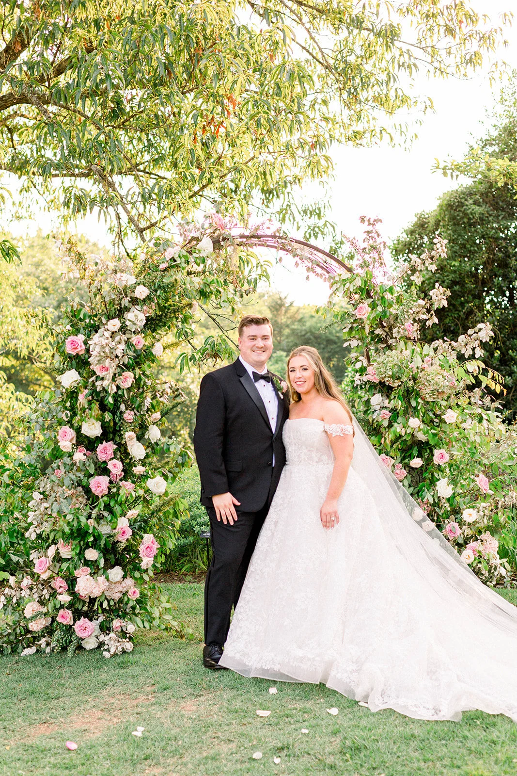 A fairytail arch filled with blush and ivory garden roses, majolica spray roses, champagne roses, eleagnus, and lush sprawling greenery. Designed by Rosemary & Finch in Nashville, TN.