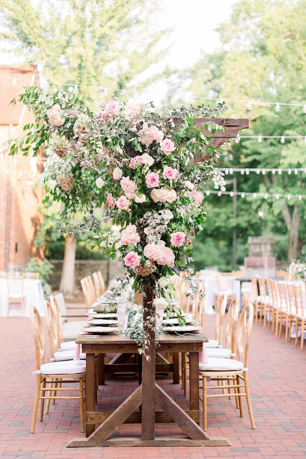 This garden courtyard reception pergola is covered with pink and ivory roses, majolica spray roses, heirloom carnations, assorted hydrangea and  cherry laurel. Designed by Rosemary & Finch in Nashville, TN.
