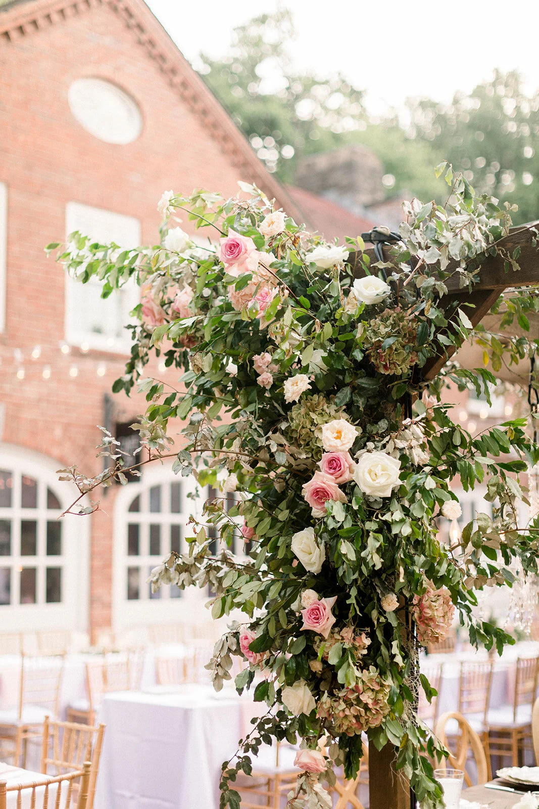 This garden courtyard reception pergola is covered with pink and ivory roses, majolica spray roses, heirloom carnations, assorted hydrangea and  cherry laurel. Designed by Rosemary & Finch in Nashville, TN.