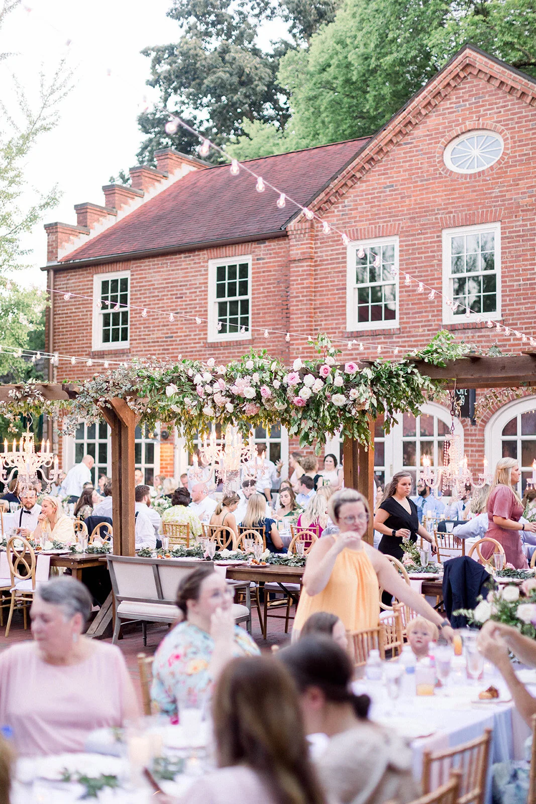 This garden courtyard reception pergola is covered with pink and ivory roses, majolica spray roses, heirloom carnations, assorted hydrangea and  cherry laurel. Designed by Rosemary & Finch in Nashville, TN.