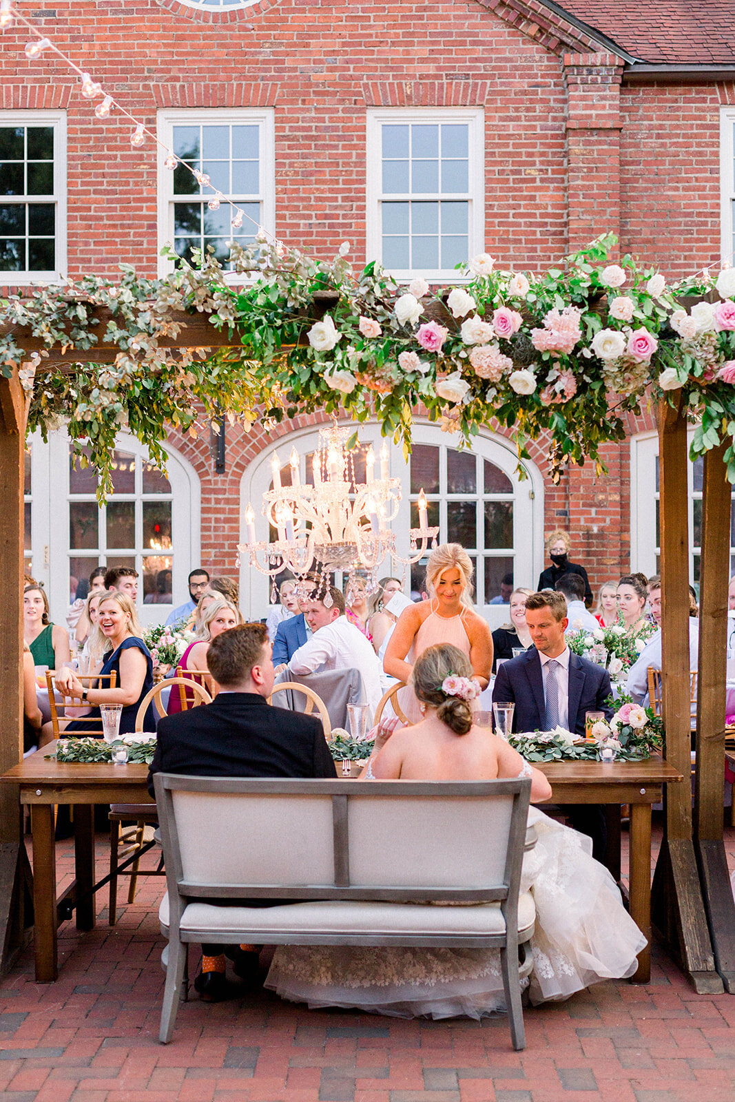 This garden courtyard reception pergola is covered with pink and ivory roses, majolica spray roses, heirloom carnations, assorted hydrangea and  cherry laurel. Designed by Rosemary & Finch in Nashville, TN.