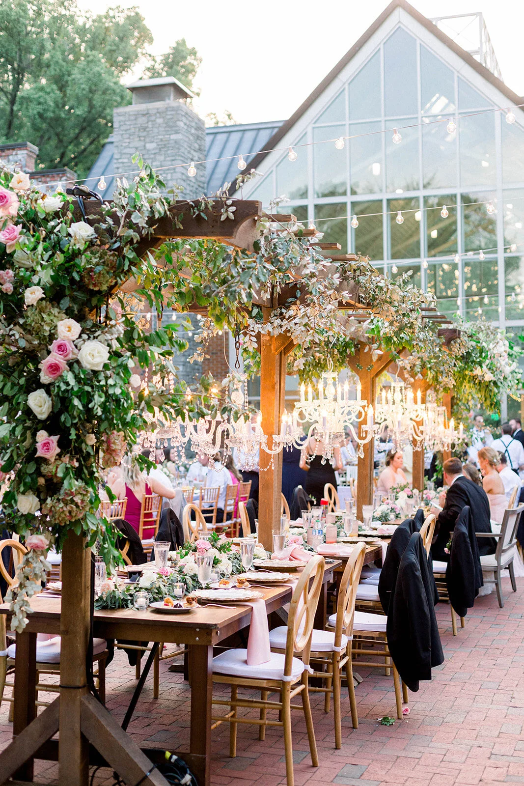 This garden courtyard reception pergola is covered with pink and ivory roses, majolica spray roses, heirloom carnations, assorted hydrangea and  cherry laurel. Designed by Rosemary & Finch in Nashville, TN.