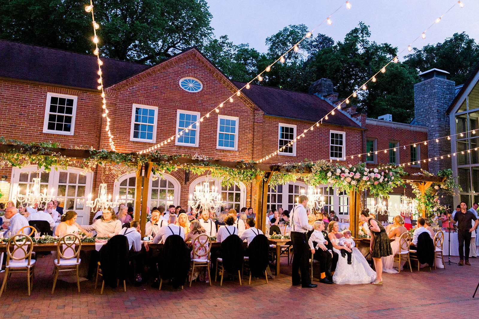 This garden courtyard reception pergola is covered with pink and ivory roses, majolica spray roses, heirloom carnations, assorted hydrangea and  cherry laurel. Designed by Rosemary & Finch in Nashville, TN.