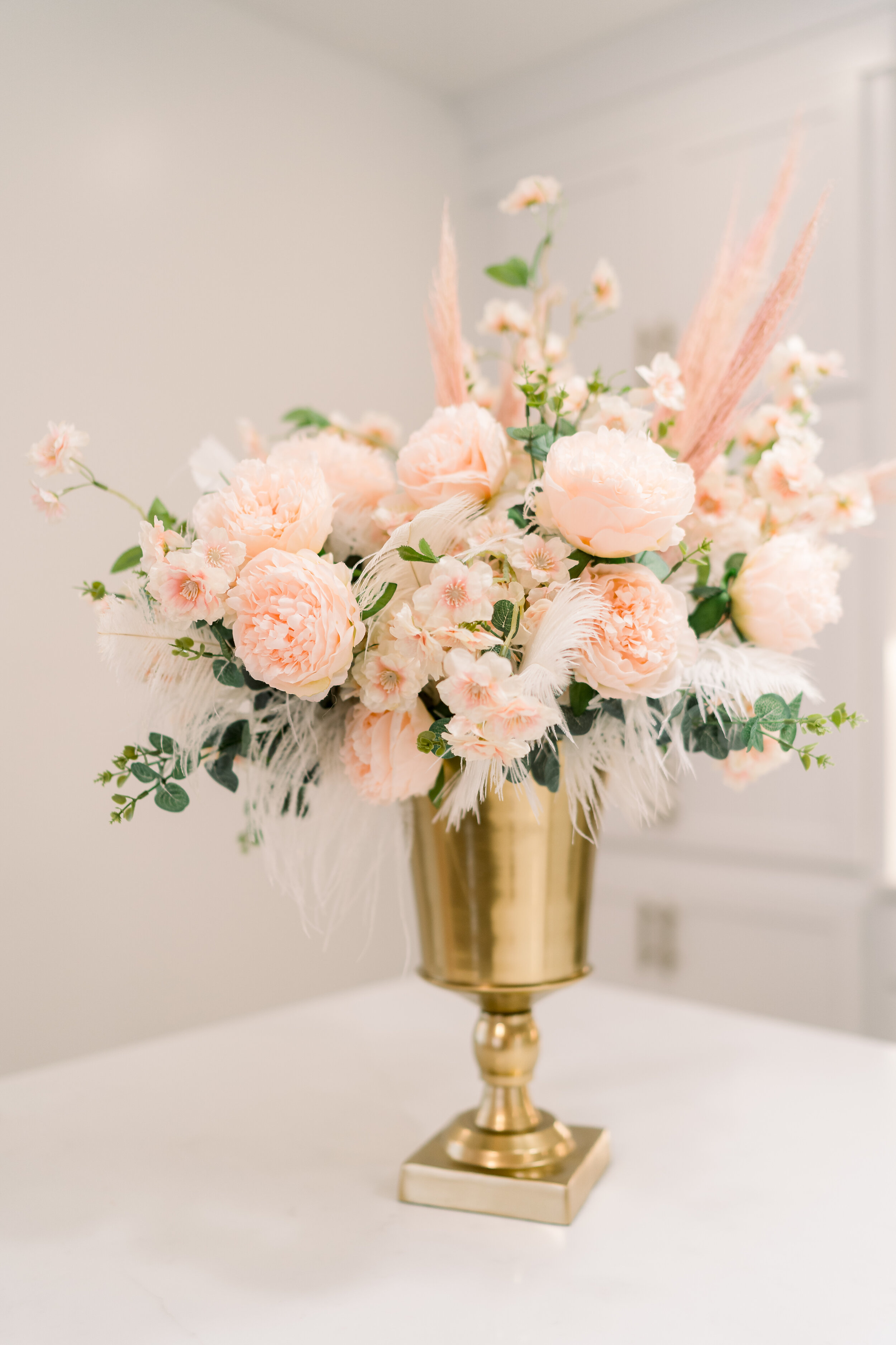 Celebration house boasts all things pink, frilly, and extra. These arrangements are no exception, filled with ostrich feathers and faux flowers like peonies, garden roses, ranunculus, cherry blossom and eucalyptus. Designed by florist Rosemary & Fin…