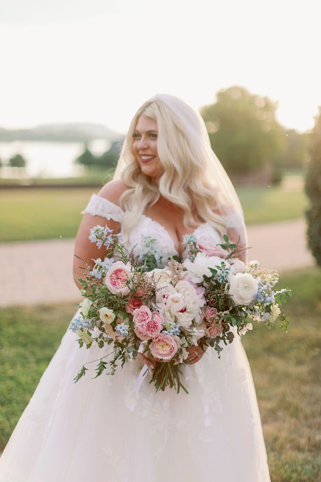 A lush bridal bouquet filled with hues of blush, pink, ivory, and hints of French blue. Garden roses, majolica spray roses, champagne roses, peonies, ranunculus, delphinium, and spirea make up this fairytale bouquet. Designed by Rosemary & Finch in N