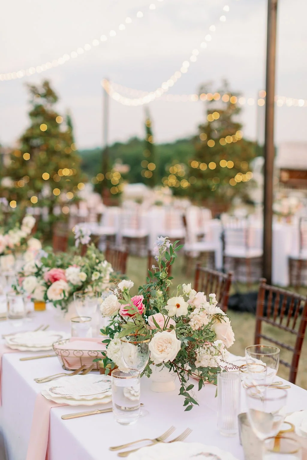 This garden-inspired reception features floral hues of blush, ivory, cream, pink, and hints of French blue along with centerpieces of pink roses, peonies, garden roses, blue delphinium, ranunculus, spirea and hydrangea. Designed by Rosemary & Finch i