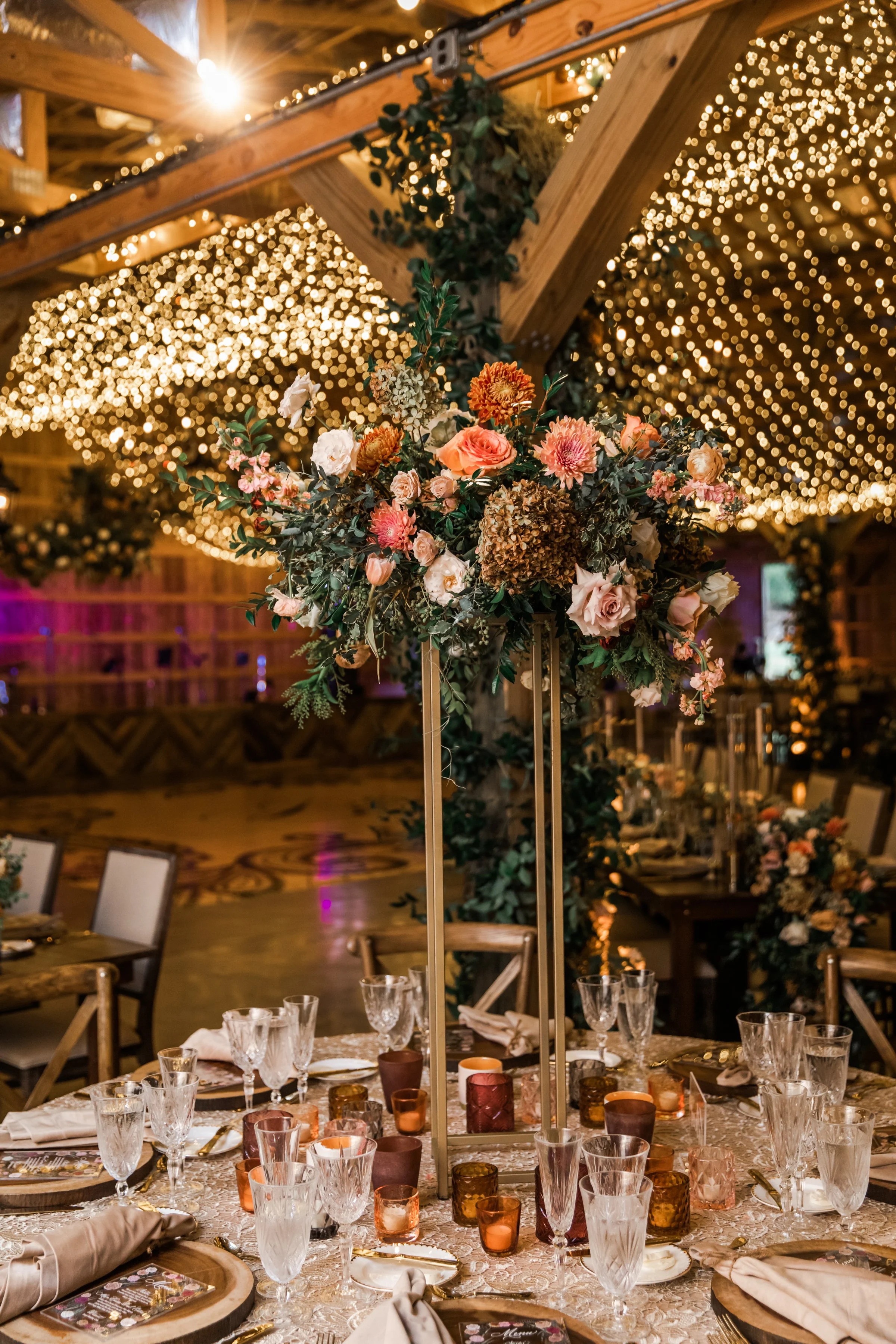 Gorgeous autumnal elevated centerpieces featuring garden roses, ranunculus, and dahlias are adorned with fairy ring candles creating hues of copper, blush, terra cotta, and yellow. Designed by Rosemary and Finch in Nashville, TN.