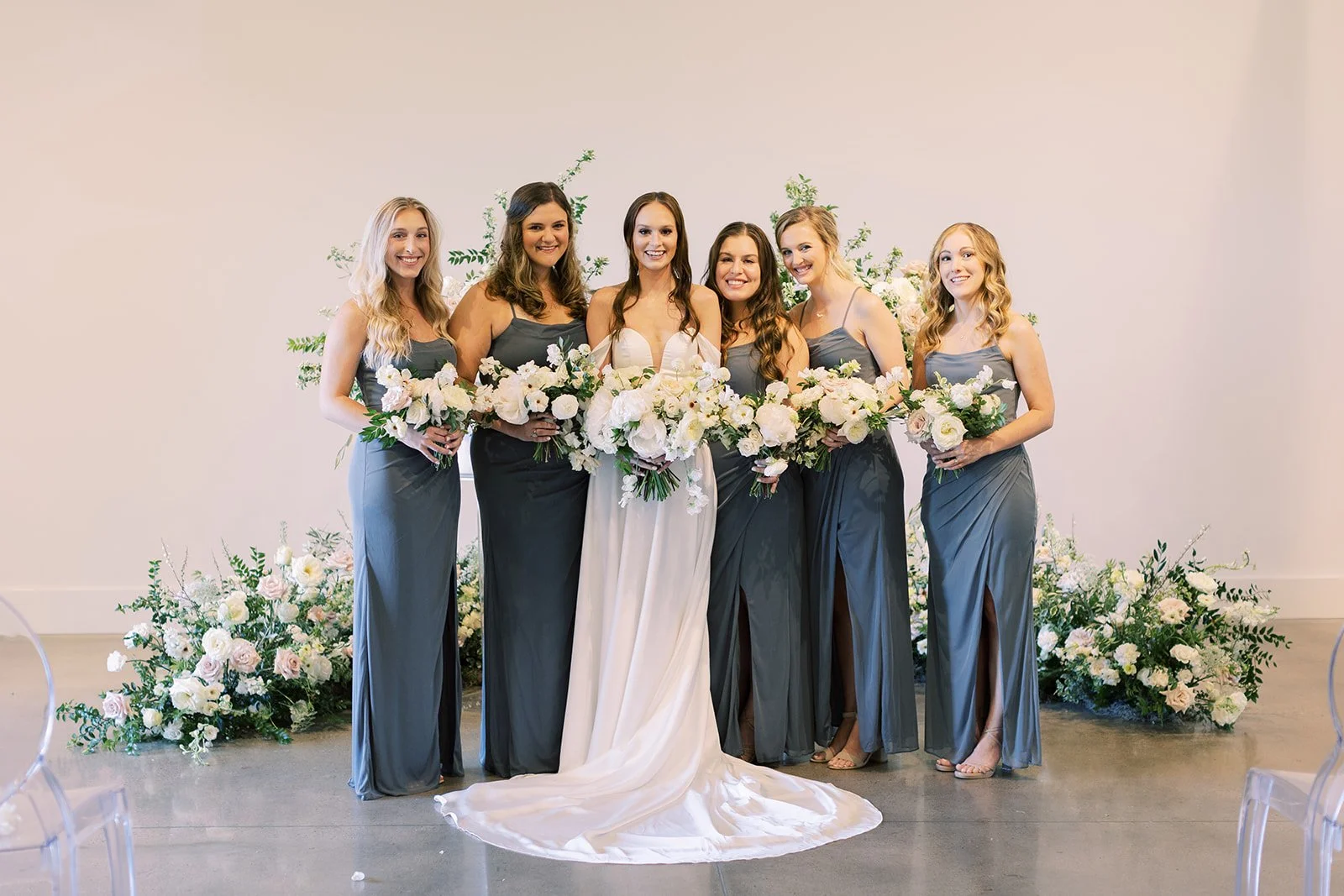Bridal party florals of white garden roses, peonies, ranunculus, sweet peas, scabiosa, butterfly ranunculus and dark greenery in floral hues of white, cream, and blush. Designed by Rosemary and Finch in Nashville, TN.