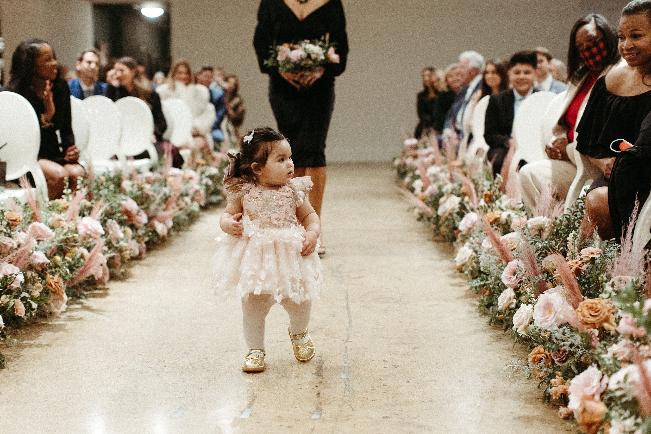 Lush aisle meadows beautifully frame the ceremony of this winter wedding with hues of dusty pink, terra cotta, cream, and sage green. Complete with petal heavy roses and pink pampas grass. Designed by Rosemary and Finch in Nashville, TN.
