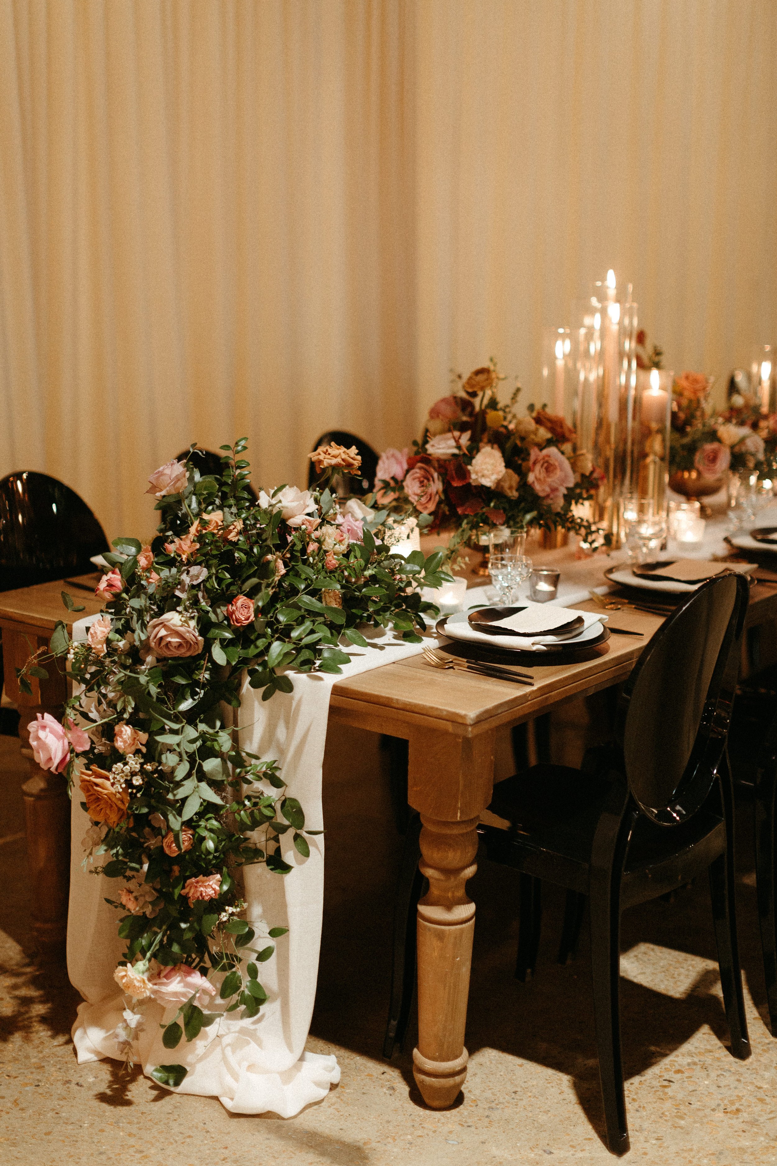 Beautiful floral cascades decorate the tables of this art deco wedding. Petal heavy roses, dried branches, and greenery bring floral hues of terra cotta, dusty pink, burgundy, and sage green. Designed by Rosemary and Finch in Nashville, TN.