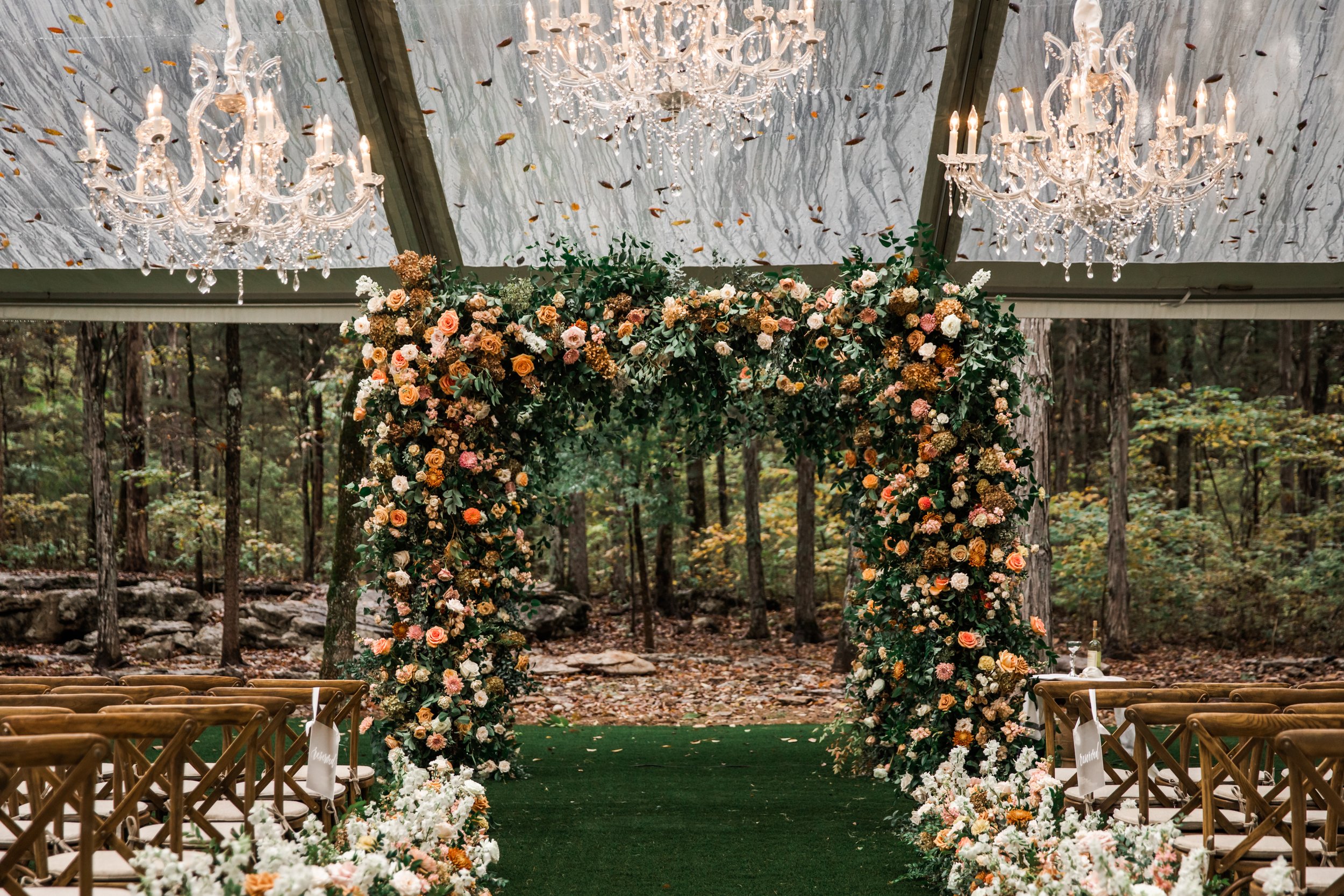 Eye-catching oversized chuppah overflowing with fall florals featuring dahlias, garden roses, rain tree pods, and fall greenery. Autumnal hues of terra cotta, dusty pink, copper, and yellow create this statement wedding piece. Designed by Rosemary an