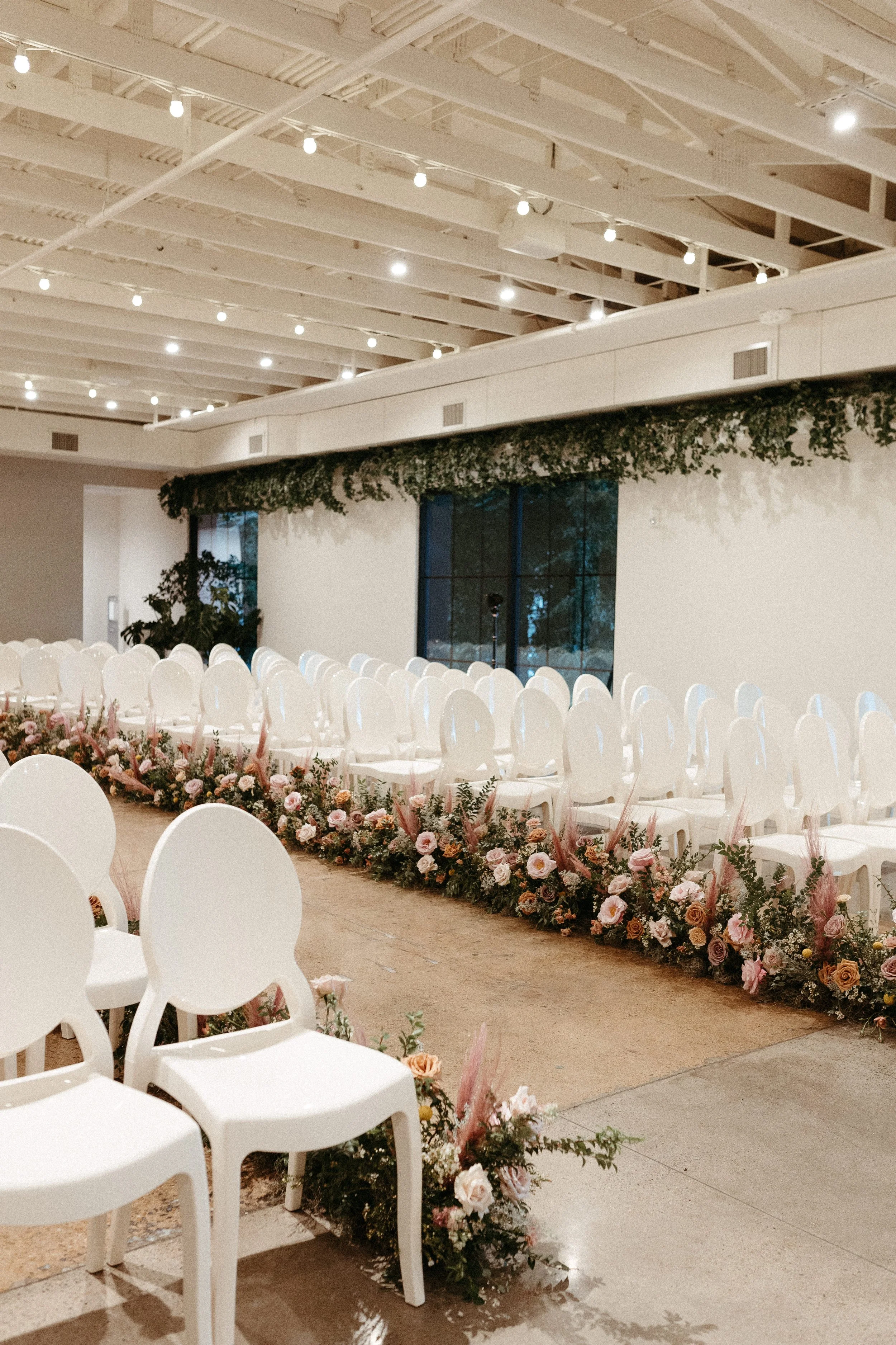 Lush aisle meadows beautifully frame the ceremony of this winter wedding with hues of dusty pink, terra cotta, cream, and sage green. Complete with petal heavy roses and pink pampas grass. Designed by Rosemary and Finch in Nashville, TN.
