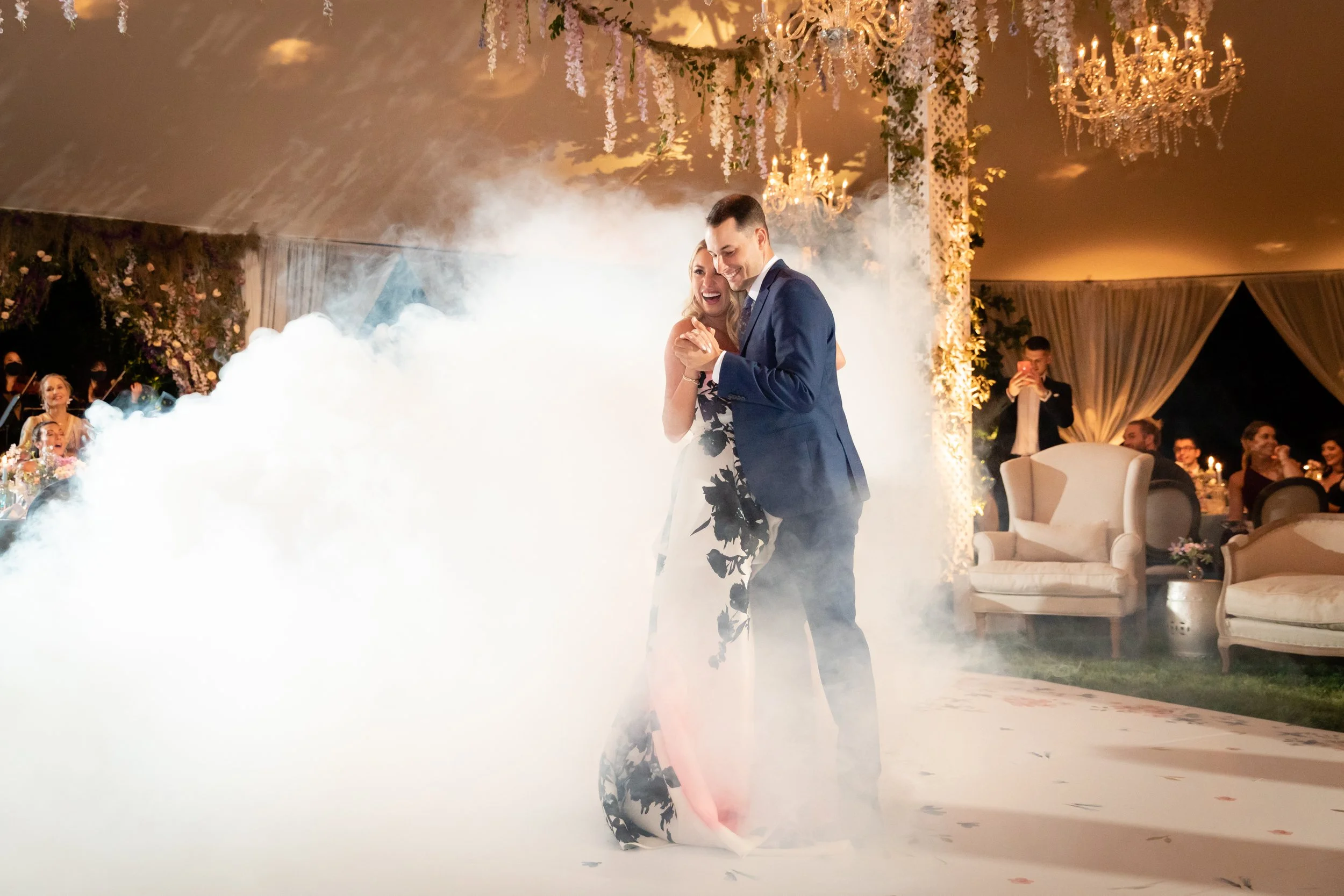 Growing, fresh floral installations and chandeliers with blush garden roses, lavender delphinium, wisteria, globe allium, and vines and greenery for a tented Bridgerton inspired engagement party at a private home in Nashville, TN.