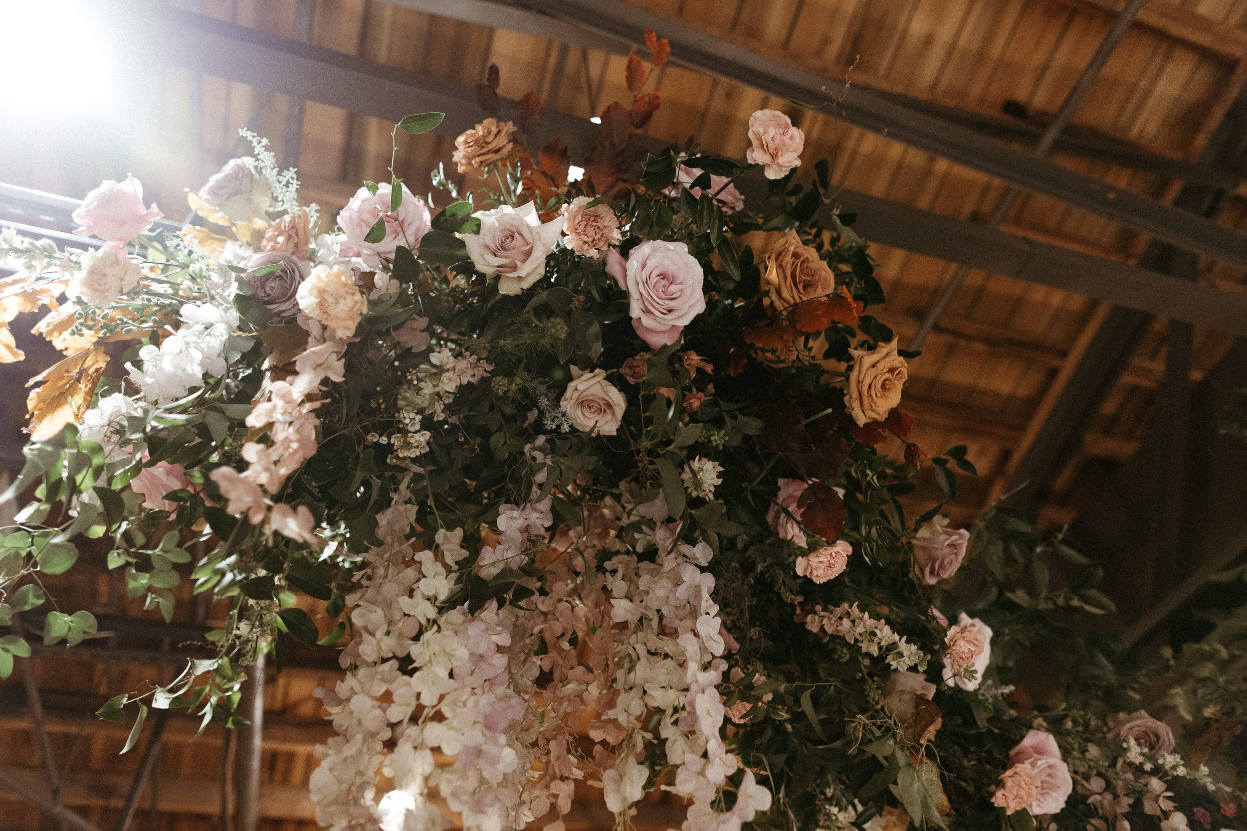Stunning floral clouds accent this Great Gatsby inspired winter wedding. Hues of terra cotta, dusty pink, burgundy, and mauve are brought to life with petal heavy roses, wisteria, and pink pampas grass. Designed by Rosemary and Finch in Nashville, TN