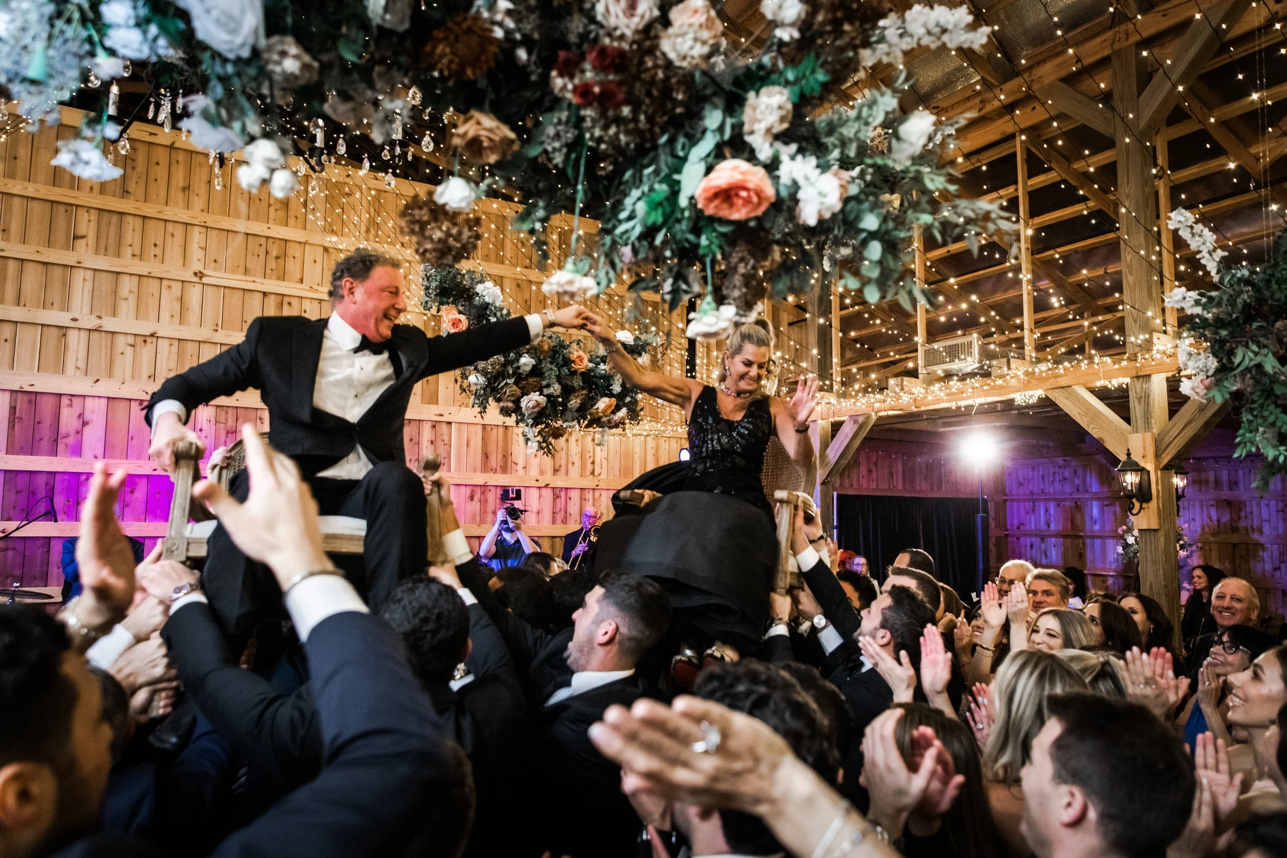 Gorgeous autumnal floral clouds hang over the dance floor, including terra cotta, rose gold, toffee, blush, and neutral florals. These clouds feature lush garden roses, ranunculus, lisianthus, and privet berries. Designed by Rosemary and Finch in Nas