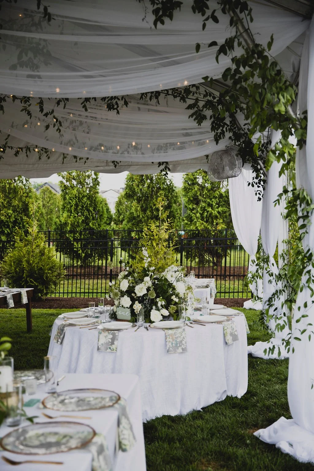 The centerpieces at this romantic summer wedding are filled with white ranunculus, garden roses, spray roses, delphinium, queen anne's lace, and lush greenery. Designed by Rosemary and Finch in Nashville, TN.