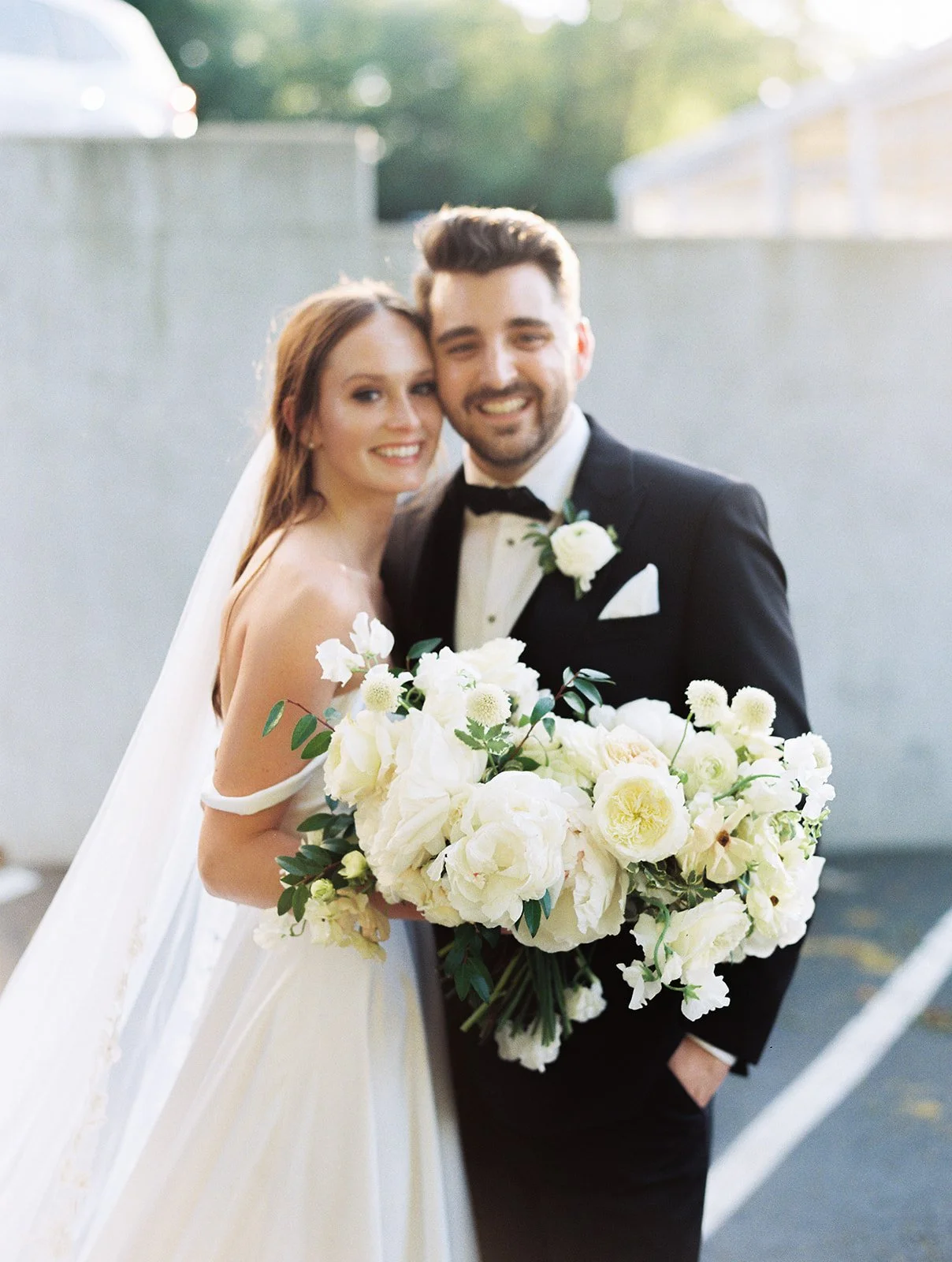 Bridal bouquet of white garden roses, peonies, ranunculus, sweet peas, scabiosa, butterfly ranunculus and dark greenery in floral hues of white, cream, and blush. Designed by Rosemary and Finch in Nashville, TN.