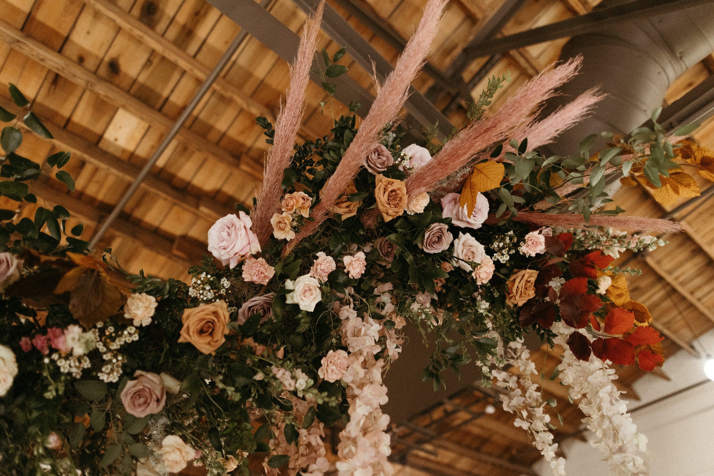 Stunning floral installations bring warmth to this Great Gatsby inspired wedding with florals of terra cotta, dusty pink, and burgundy hues. Petal heavy roses, copper beech, and pink pampas grass accents. Designed by Rosemary and Finch in Nashville,