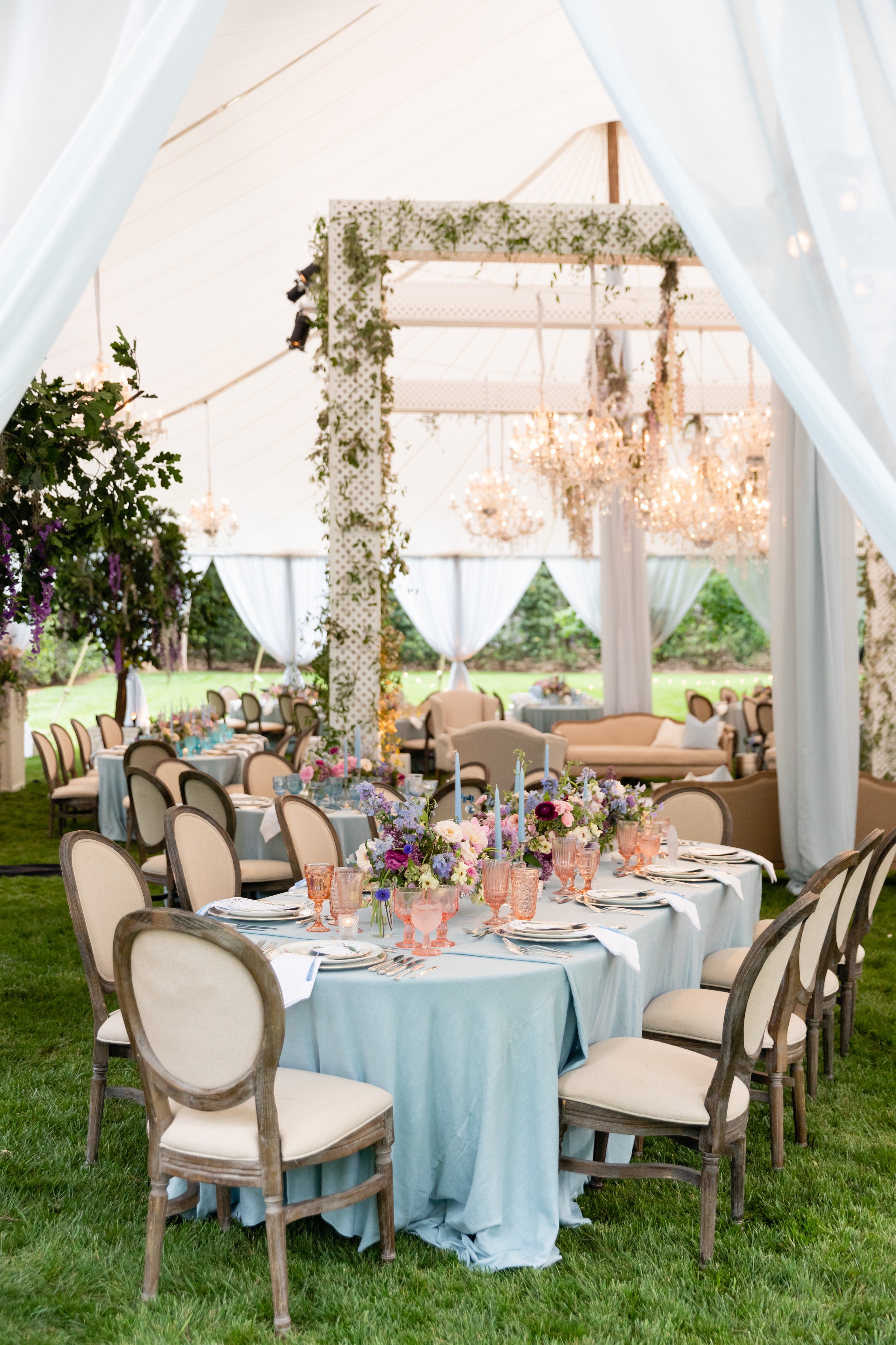 Growing, fresh floral centerpieces with blush garden roses, lilac, blue sweet peas, ranunculus, lavender delphinium, globe allium, and natural greenery for a tented Bridgerton inspired engagement party at a private home in Nashville, TN. Flower by Te