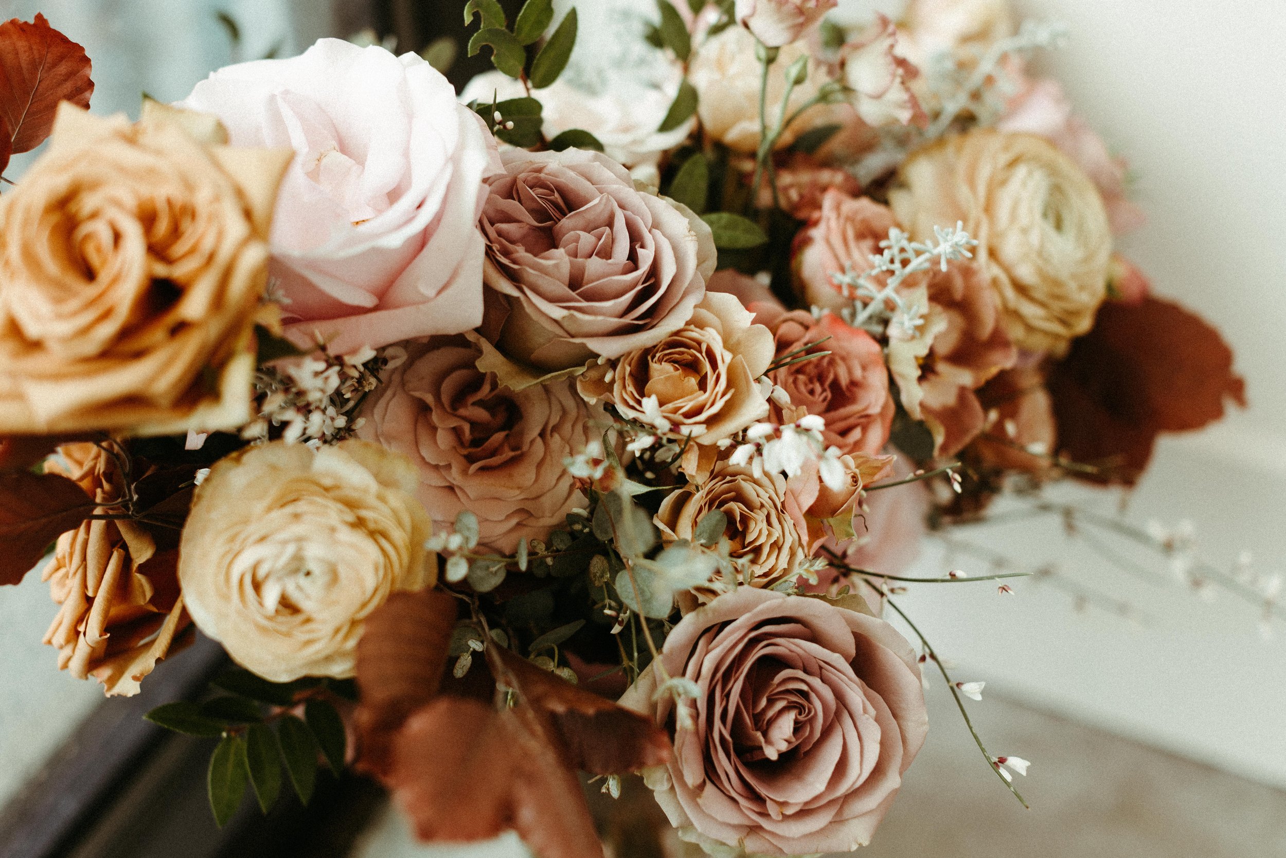 This elegant bridal bouquet brought hues of mauve, dusty pink, cream, burgundy, and terra cotta to this winter wedding. Lush with petal heavy roses, ranunculus, spray roses, copper beech, and greenery. Designed by Rosemary and Finch in Nashville, TN.