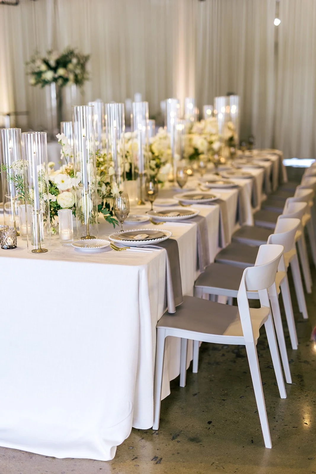 Low floral centerpieces for elegant wedding overflowing with white garden roses, ranunculus, butterfly ranunculus, scabiosa, lisianthus, sweet peas, and natural dark greenery. Floral hues of white, cream, and blush. Designed by Rosemary and Finch in