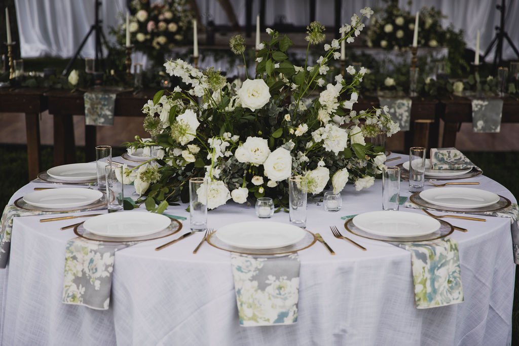 The centerpieces at this romantic summer wedding are filled with white ranunculus, garden roses, spray roses, delphinium, queen anne's lace, and lush greenery. Designed by Rosemary and Finch in Nashville, TN.