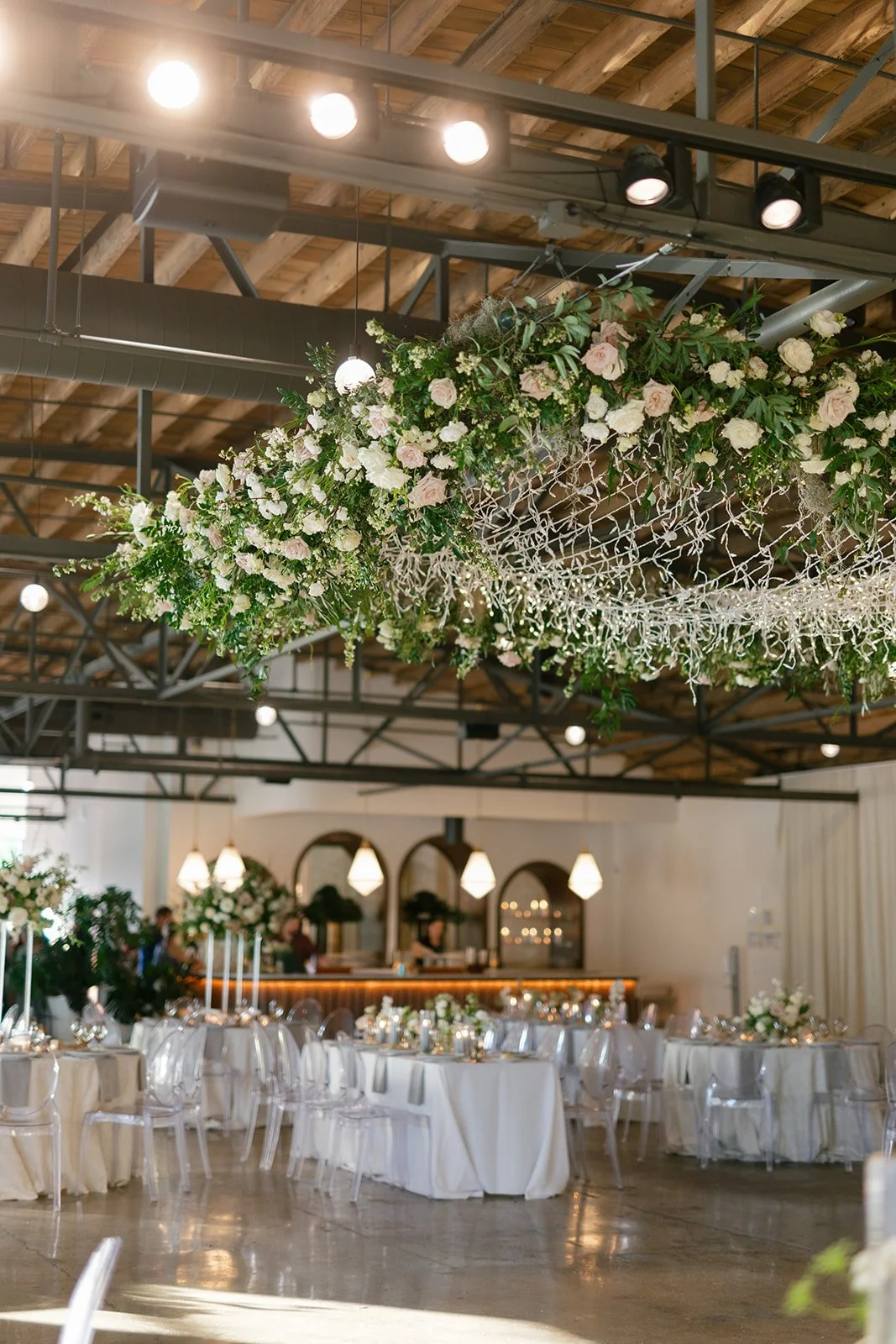 Lush floral chandelier lights up the dance floor with florals of petal heavy roses, ranunculus, lisianthus, delphinium, and dark greenery in hues of white, cream, and blush. Designed by Rosemary and Finch in Nashville, TN.