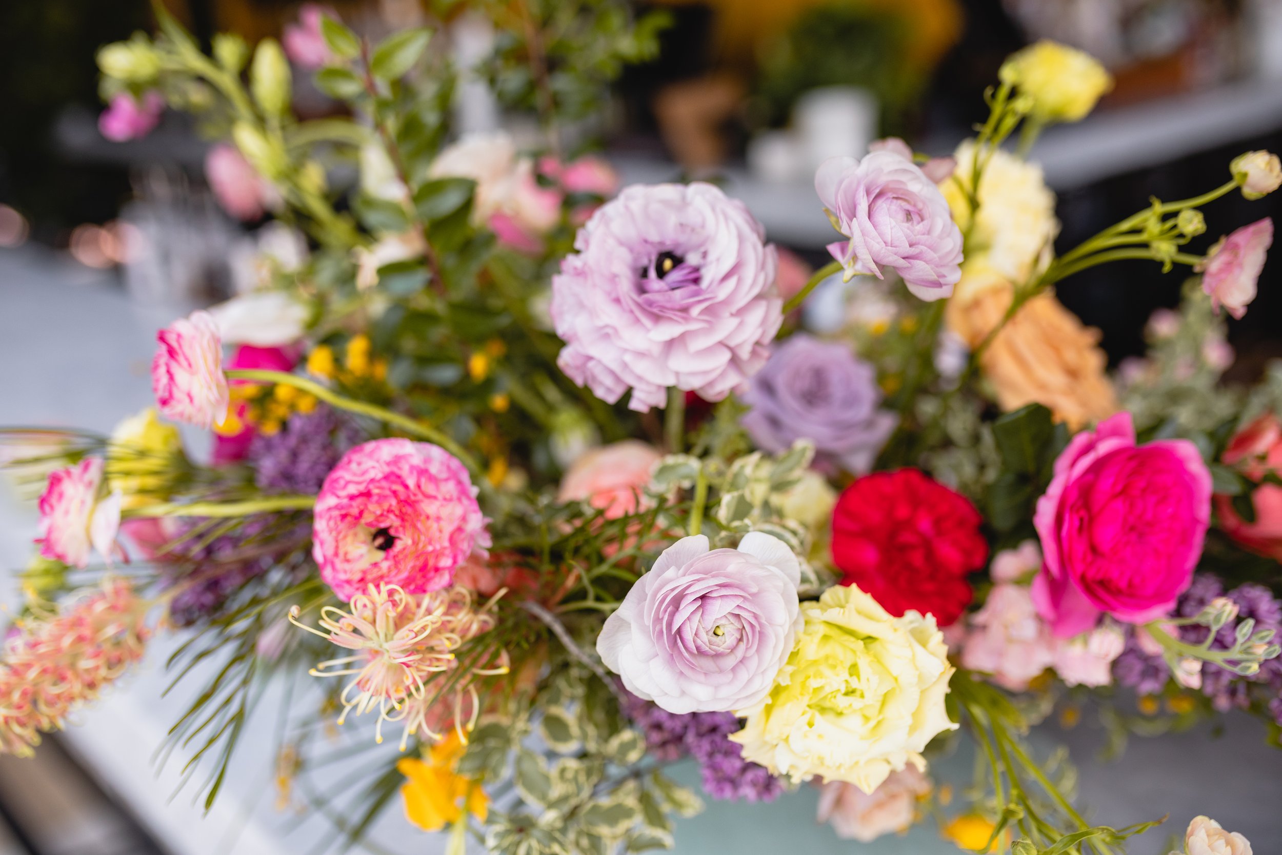 Bright spring floral hues of pink, lavender, coral, magenta, and yellow inspire the event space of Fifth + Broadway in Nashville, TN. Florals composed of roses, ranunculus, sweet peas, butterfly ranunculus, mixed greenery. Design by Rosemary and Finc