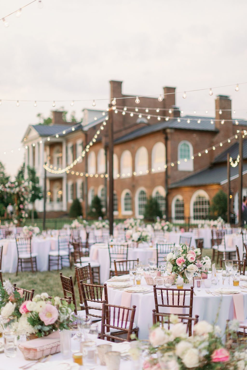 This garden-inspired reception features floral hues of blush, ivory, cream, pink, and hints of French blue along with centerpieces of pink roses, peonies, garden roses, blue delphinium, ranunculus, spirea and hydrangea. Designed by Rosemary & Finch i